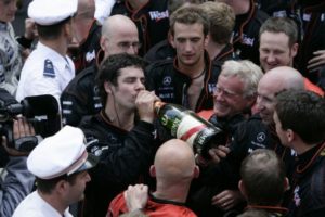Marc Priestley takes a swig of the bubbly with his colleagues waiting and Kimi Raikkonen (top left) watching with a smile